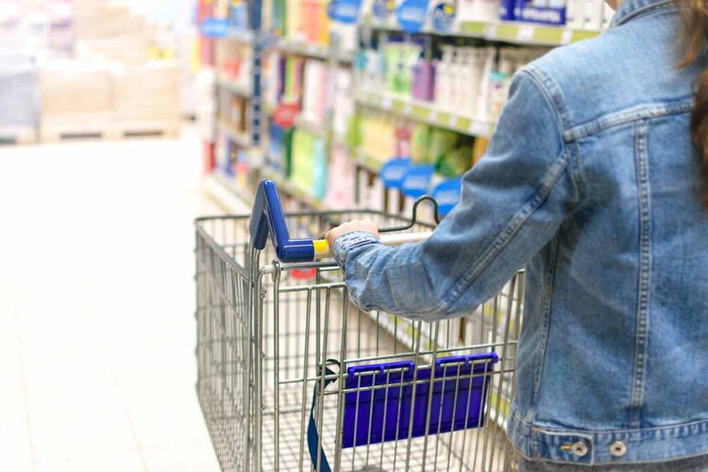 Young woman pushing empty shopping cart in a supermarket