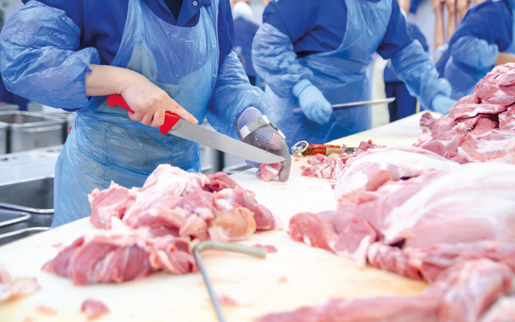Butchers are cutting pork. Line of production of sausage delicacies.