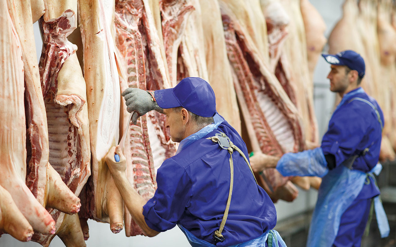 Butcher cutting pork  at the meat manufacturing.