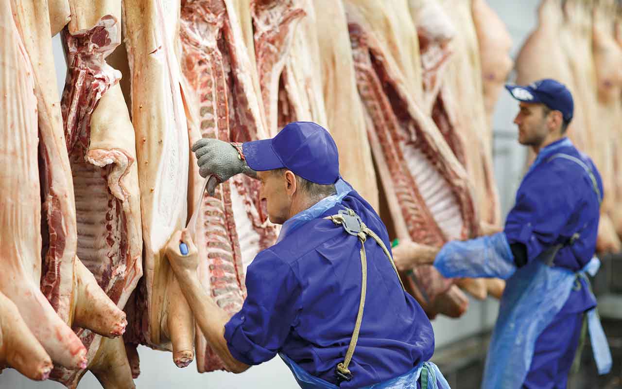 Butcher cutting pork  at the meat manufacturing